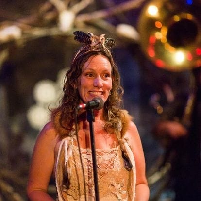Marissa Percoco, Executive Director of Firefly Gathering at the Annual Gala wearing a costume and speaking into a mic