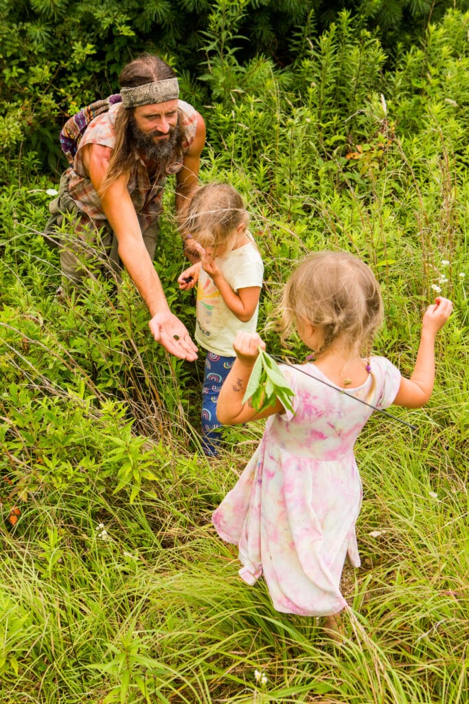 A parent holds out a bug in his hand to one of his children
