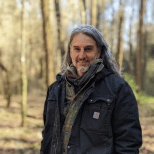Jason Cannoncro stands in the woods in winter, wearing a jacket and smiling