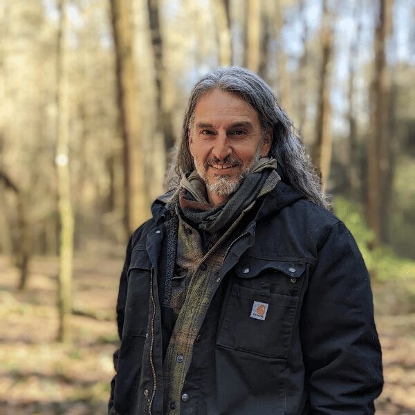 Jason Cannoncro stands in the woods in winter, wearing a jacket and smiling